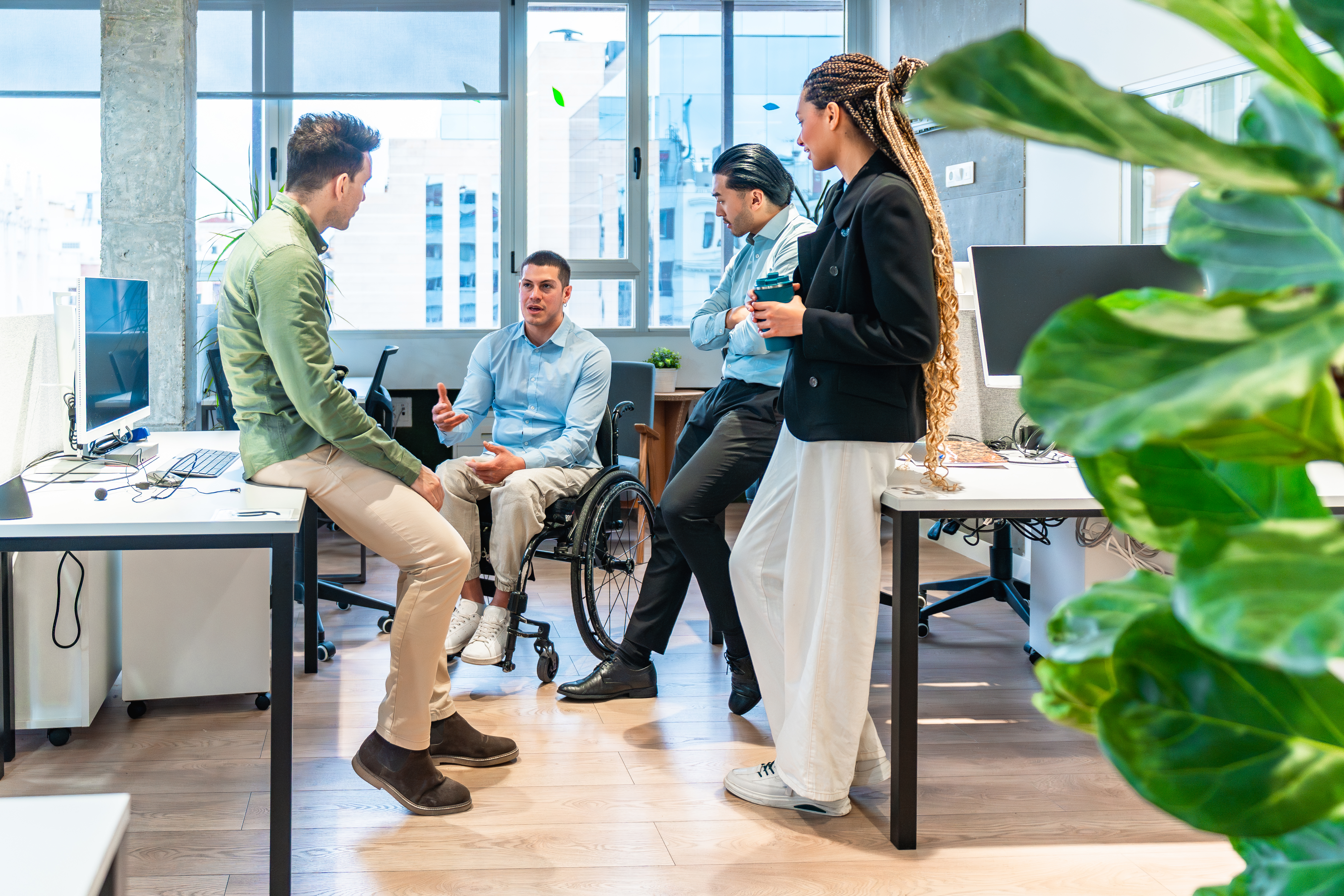 Diverse business team collaborating in modern office with disabled colleague