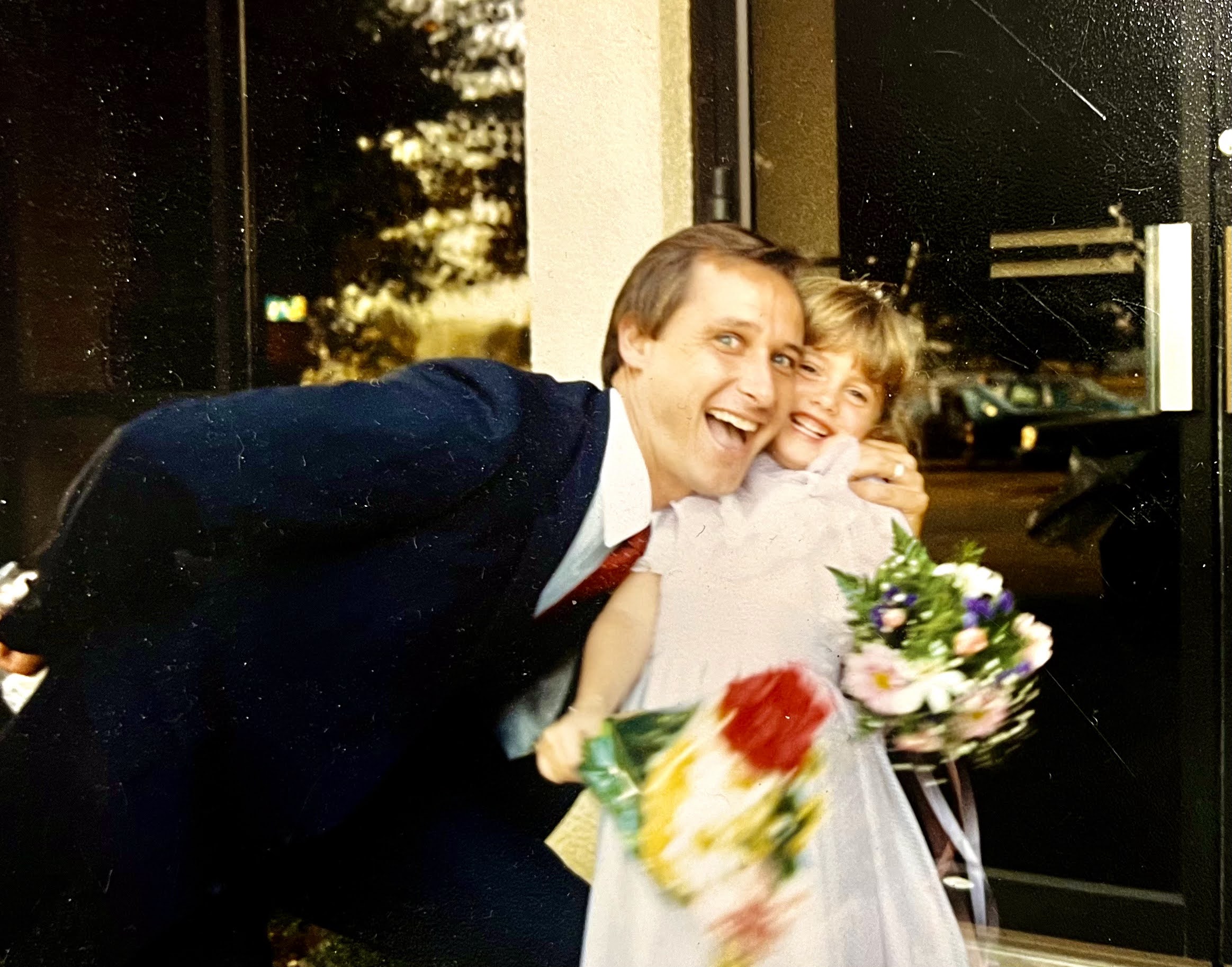 The author Jennifer Moffett pictured as a young girl, smiling and laughing with her stepdad.