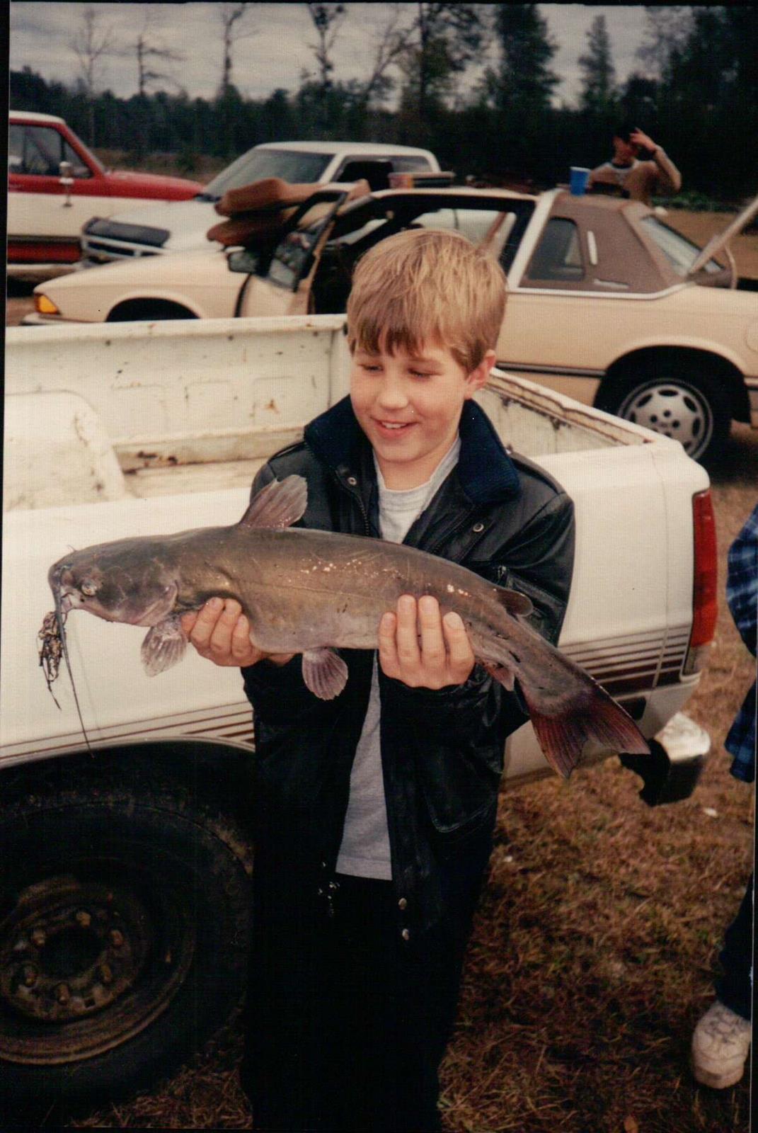 Bubba Randall's son Jessie pictured as a young boy, smiling and holding a huge fish.