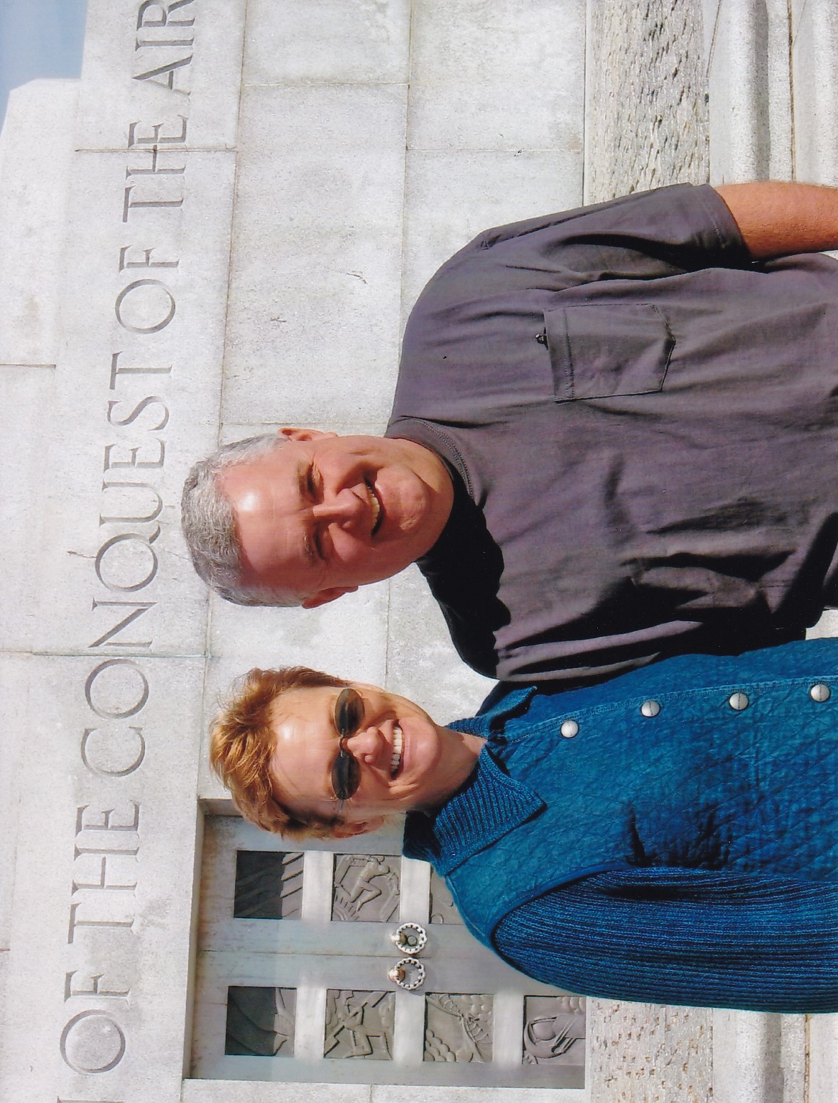 The author Julie Blehm standing next to her husband David. Both are smiling, and it's bright and sunny outside.