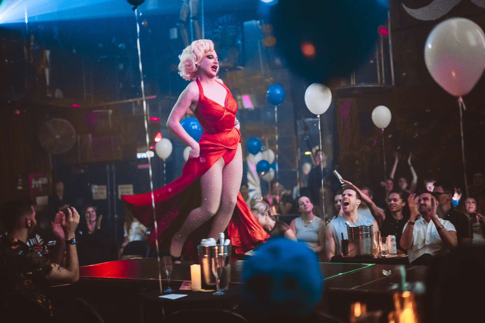 Drag performer wearing a red dress, performing in front of an audience