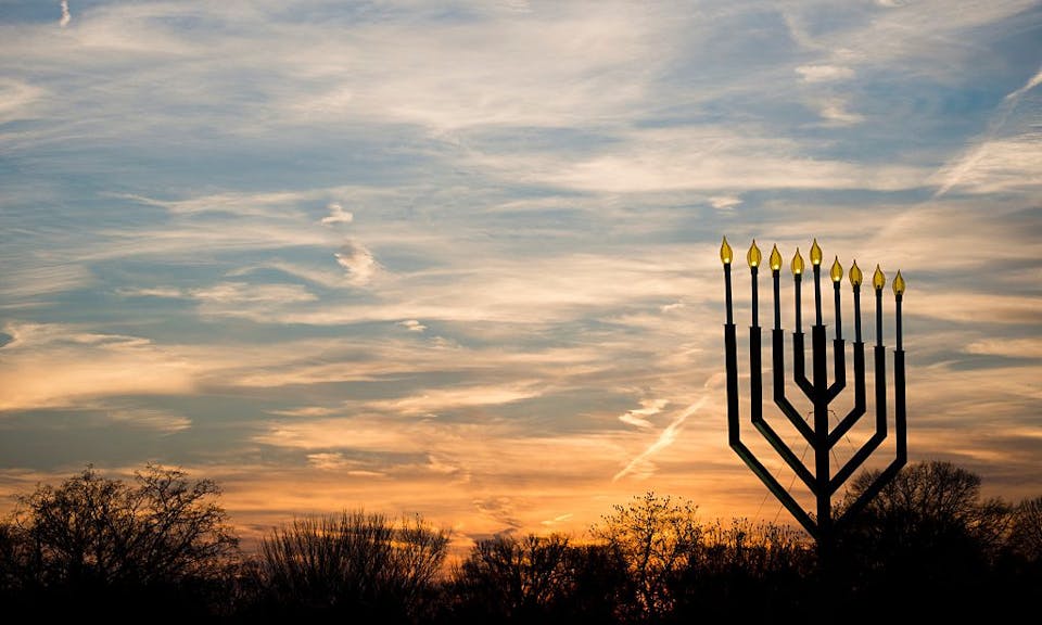 The National Menorah, part of the Jewish holiday of Hanukkah, is silhouetted against the setting sun in Washington, DC on December 10, 2015.
The holiday commemorates the re-dedication of the holy temple in Jerusalem after the Jews’ 165 B.C. victory over the Hellenist Syrians when Antiochus, the Greek King of Syria, outlawed Jewish rituals and ordered the Jews to worship Greek gods. / AFP / Andrew Caballero-Reynolds        (Photo credit should read ANDREW CABALLERO-REYNOLDS/AFP via Getty Images)