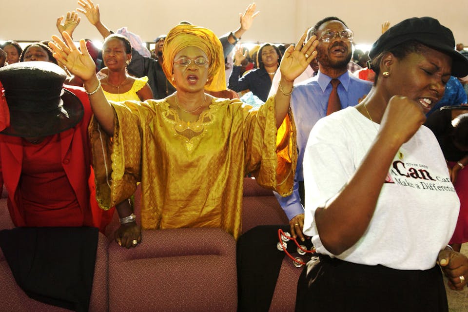 Nigerian Christians pray together at the City of David Church in Lagos, Nigeria, on September 28, 2003. *Photo by Jacob Silberberg via Getty Images*. LAGOS, NIGERIA – SEPTEMBER 28: Nigerian Christians pray together at the City of David Church September 28, 2003 in the affluent Victoria Island section of Lagos, Nigeria. Evangelical and Pentecostal churches in Nigeria are not only the domain of the nation’s poor, but also of its very wealthy. Evangelical and Pentecostal Christianity are spreading in many parts of the developing world, often outgrowing traditional forms of Christianity first brought by colonizers and long dominant. (Photo by Jacob Silberberg/Getty Images)
