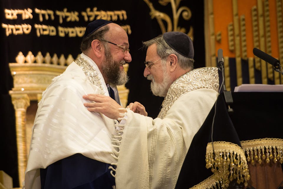 Rabbi Lord Jonathan Sacks, right, congratulates Ephraim Mirvis, his successor as chief rabbi of the United Hebrew Congregations of the UK and the Commonwealth, during a ceremony at the St. John's Wood Synagogue in north London on September 1, 2013. *STEFAN ROUSSEAU/AFP via Getty Images*. Spitzer MO Main
