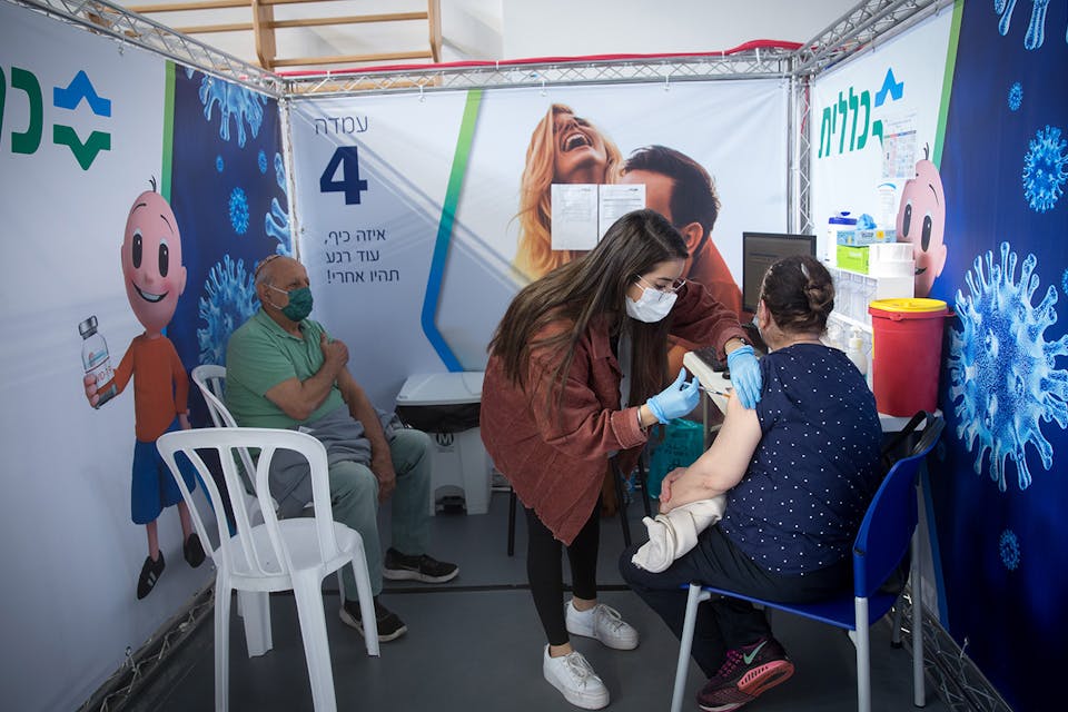 Israelis receive coronavirus vaccines at a sports hall turned vaccination center in Petah Tikva on January 27, 2021. *Miriam Alster/Flash90*. Berens Vaccine Main