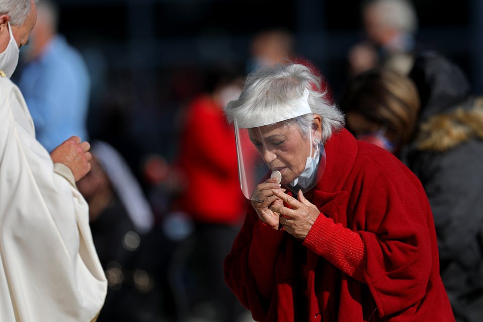 A parishioner takes communion while attending a Christmas Day mass given outdoors on Friday, Dec. 25, 2020 in Garden Grove, CA. *Gary Coronado/Los Angeles Times via Getty Images*. Corona Mass Main