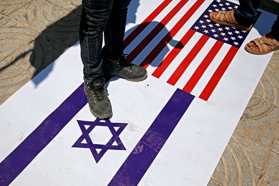 Palestinians trample a poster on the ground depicting the flags of Israel and the US on July 7, 2020. *MOHAMMED ABED/AFP via Getty Images*. Roga Beinart Main