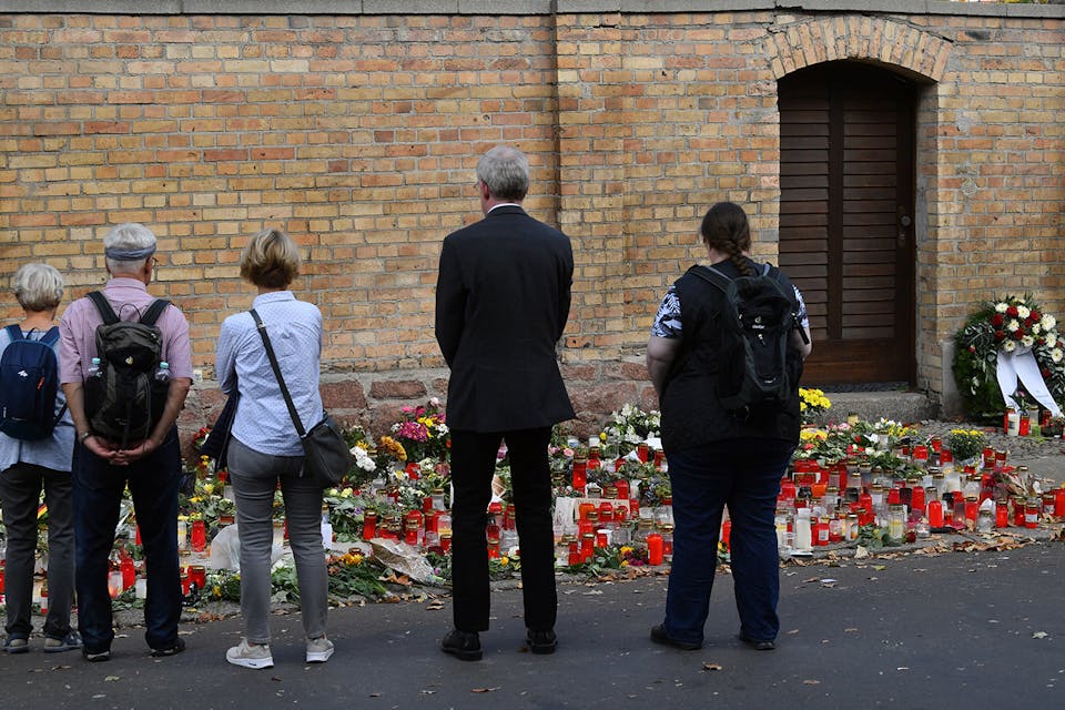 *People standing in front of candles and flowers at the synagogue in Halle, Germany after a right-wing extremist attack on October 9, 2019.* Photo by Hendrik Schmidt via Getty Images. Halle Main
