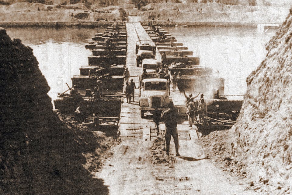 *Egyptian military trucks cross a bridge laid over the Suez Canal on October 7, 1973 during the Yom Kippur War.* CIA via Wikipedia. Bridge_Crossing