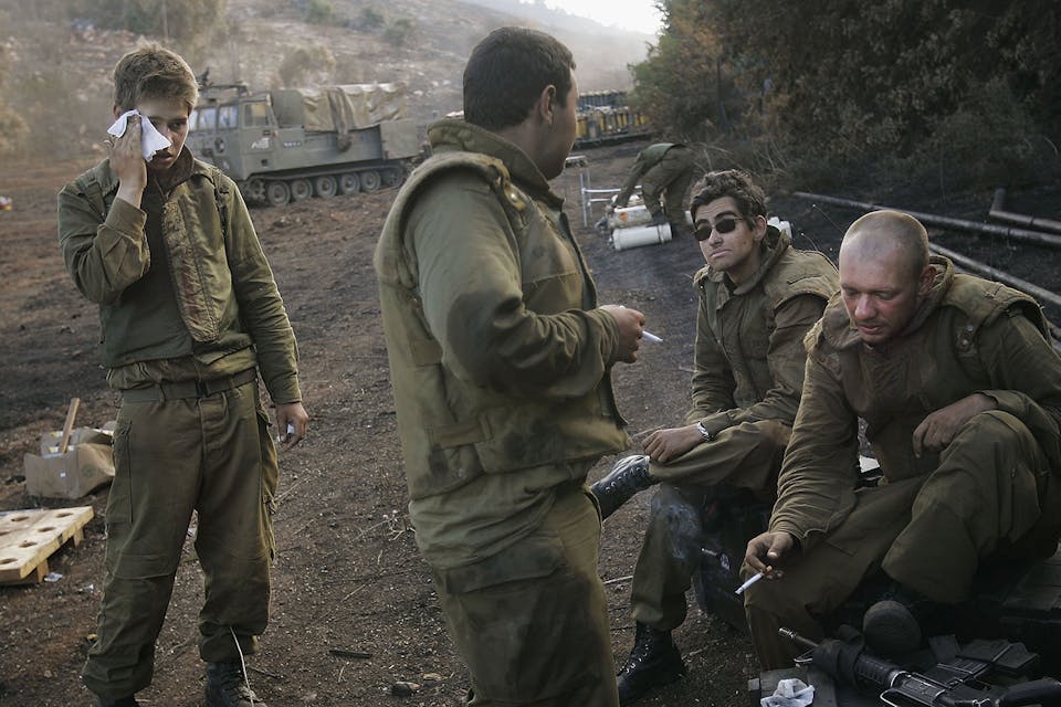 *Israeli artillery soldiers, covered in dirt from their work, take a break between firing 155mm shells into Lebanon on August 13, 2006.* Chris Hondros/Getty Images. Friedman Main