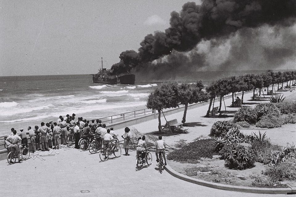 *The *Altalena* on fire after being shelled near Tel Aviv in June 1948.* Wikipedia. 1280px-Altalena_off_Tel-Aviv_beach