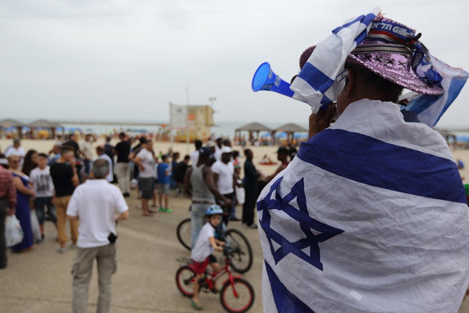*A man wrapped in an Israeli flag walks on the beach in Tel Aviv during celebrations on Israel's 66th Independence Day, May 6, 2014.* Yaakov Naumi/Flash 90. Independence-Day