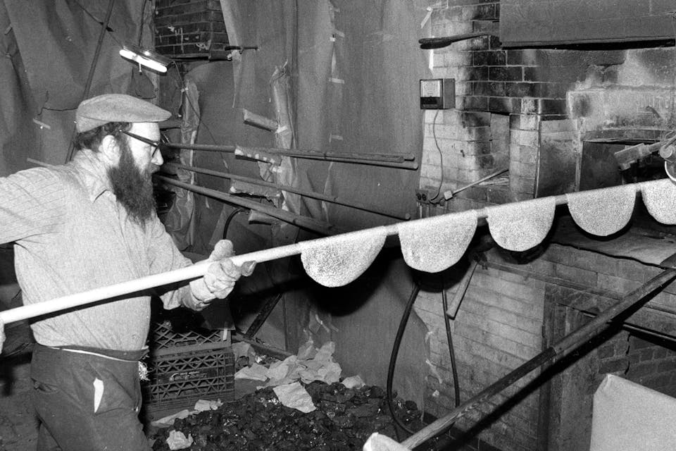 A man baking round handmade *shmurah* matzah. *Anthony Pescatore/NY Daily News Archive via Getty Images.* MATZAH-FACTORY