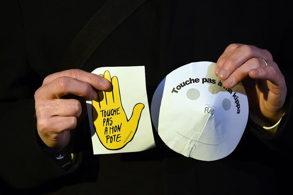 A protester in Marseilles holds a *kippah* made of paper and a sign reading "Don't touch my *kippah"* and "Don't touch my pal." *ANNE-CHRISTINE POUJOULAT/AFP/Getty Images*. Kippah-Yarmulke