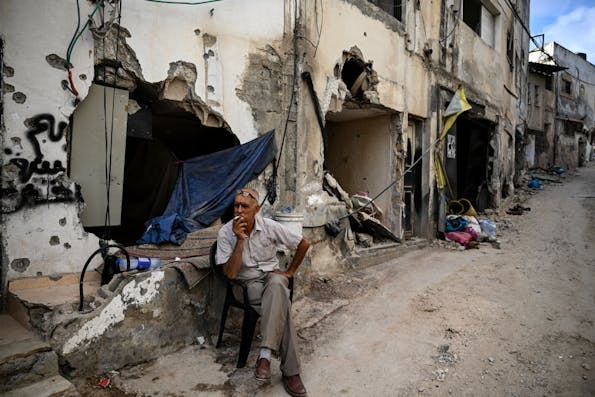 TOPSHOT – A man sits in front of a damaged building following an Israeli military raid in the Jenin refugee camp, in the occupied West Bank on September 6, 2024. Israeli forces withdrew from Jenin in the occupied West Bank on September 6 after a deadly 10-day operation, witnesses said, as Hamas blamed Israel for deadlock in Gaza truce talks. (Photo by RONALDO SCHEMIDT / AFP) (Photo by RONALDO SCHEMIDT/AFP via Getty Images)