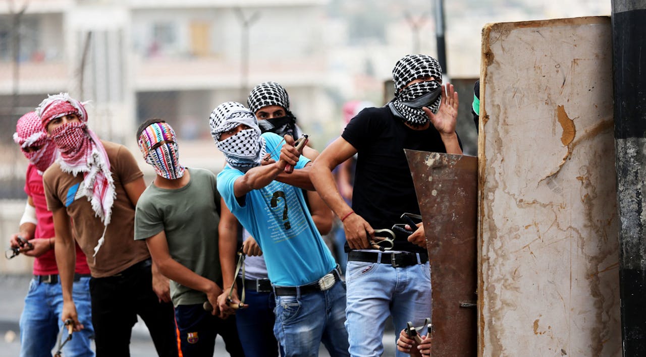 *Masked Palestinian youths use slingshots to hurl rocks and marbles at an Israeli military checkpoint in Bethlehem, West Bank on October 23, 2015.* Anna Ferensowicz/Pacific Press/LightRocket via Getty Images. Polisar-Main