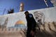 A Palestinian Authority policeman walks outside a police station adorned with a painting depicting late Palestinian leader Yasser Arafat, in the West Bank city of Hebron, on November 11, 2024, during the 20th anniversary of Arafat’s death, amid increased violence in Israeli-occupied Palestinian territory as the war between Israel and the Hamas movement continues in the Gaza Strip. (Photo by HAZEM BADER / AFP) (Photo by HAZEM BADER/AFP via Getty Images)