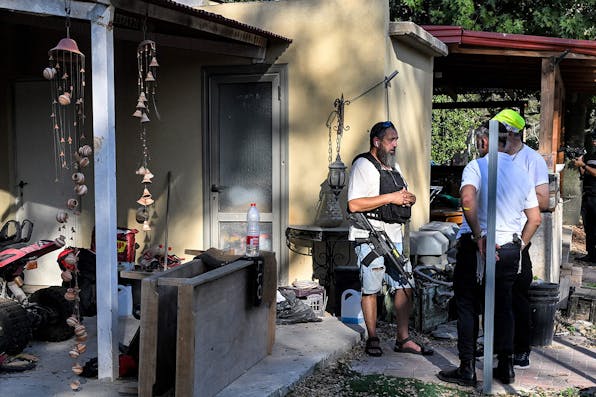 An armed speaks with one of the volunteers of ZAKA, the haredi-run NGO, at a house attacked by Hamas on October 26, 2023 in in Kibbutz Holit. *YURI CORTEZ/AFP via Getty Images*. Pfeffer Gaza