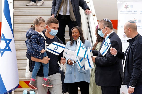 Pnina Tamano-Shata, Israel’s Minister of Immigration and Absorption, and Yaakov Hagoel, head of the World Zionist Organization, hand out Israeli flags to immigrants from Ukraine at Ben-Gurion Airport in Lod on February 20, 2022. *JACK GUEZ / AFP) (Photo by JACK GUEZ/AFP via Getty Images*. Pfeffer Law of Return