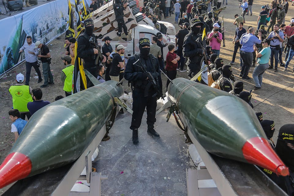 A fighter from the Saraya al-Quds Brigades, the armed wing of the Palestinian Islamic Jihad movement, stands between two rockets during a parade on the streets of Gaza City. *Mahmoud Issa/SOPA Images/LightRocket via Getty Images*. Gaza Missiles