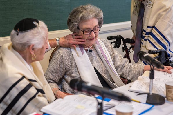 Charlotte Markowitz, 85, congratulates Sy Laufe, 90, after Sy read from the Torah at their bat mitzvah ceremony, at the Five Star Residences in Chevy Chase, Maryland, May 14, 2016. *Evelyn Hockstein/For The Washington Post via Getty Images.* Gordis LW Main