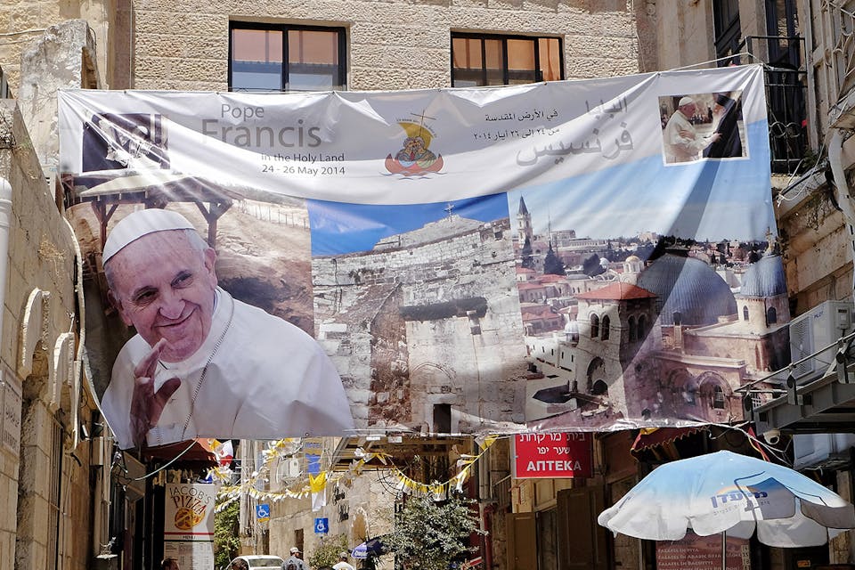 *A banner welcoming Pope Francis hangs near the Old City in Jerusalem on May 28, 2014.* AP Photo/Robert E. Klein. D’Costa LW