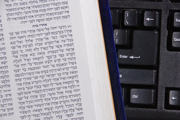 *rabbisacks.org.* concept of online bible study illustrated with hebrew bible against computer keyboard