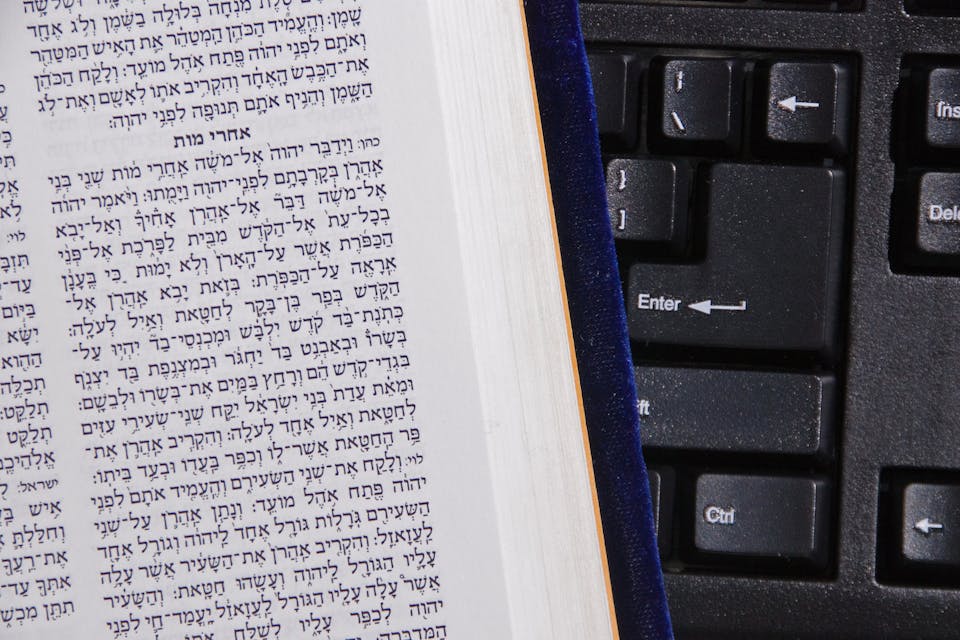 *rabbisacks.org.* concept of online bible study illustrated with hebrew bible against computer keyboard