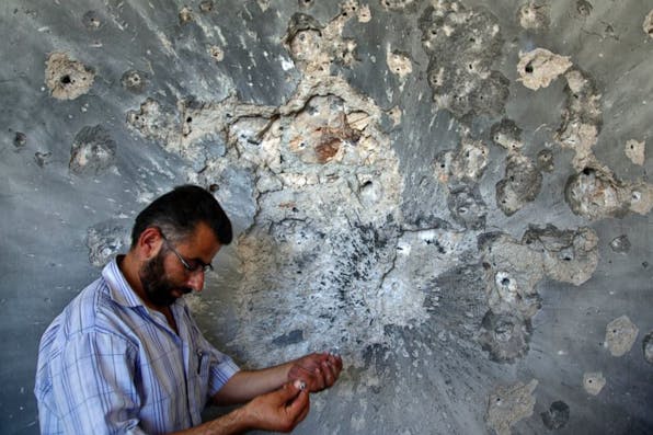 *A Syrian man holds bullets he picked from the wall of a damaged house in the town of Atareb, on the outskirts of Aleppo.* AP Photo/Khalil Hamra. Haivry-Final
