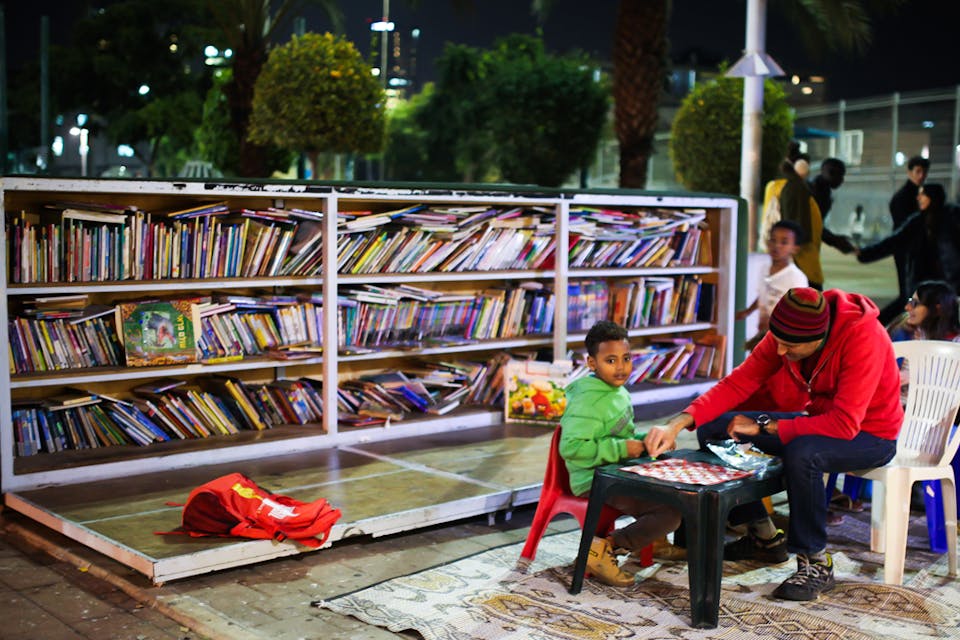 *A child and a man sit together at an outdoor book garden in Tel Aviv, December 9, 2015.* Esther Rubyan/Flash90. Horn