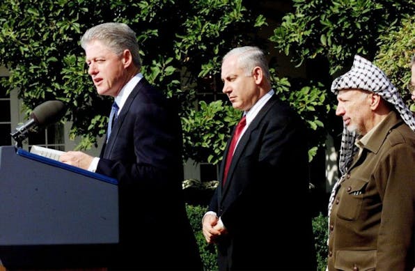 WASHINGTON, DC – OCTOBER 15:  US President Bill Clinton (L) speaks at a Middle East Peace Accords ceremony in the Rose Garden of the White House in Washington, DC as Israeli Prime Minister Benjamin Netanyahu (C) and Palestinian leader Yasser Arafat (R) look on15 October. All three leaders are scheduled to attend a tri-lateral summit on Middle East peace at the 1,000 acre secluded Wye River Plantation conference center located on the Eastern shore of Maryland.   (ELECTRONIC IMAGE)  (Photo credit should read PAUL RICHARDS/AFP via Getty Images)