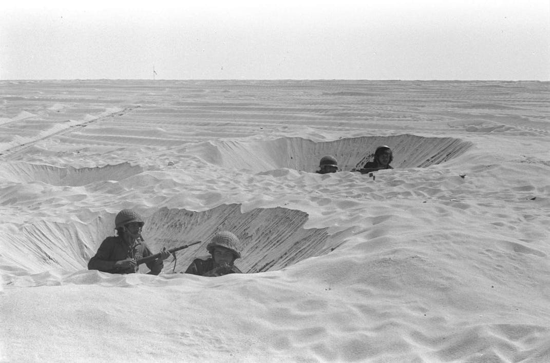SINAI DESERT, EGYPT – OCTOBER 14: (FILE PHOTO) Israeli soldiers take cover in their foxholes during fighting against the Egyptians October 14, 1973 in the Sinai Desert during the Yom Kippur War. Israeli Prime Minister Ariel Sharon, then an Israeli general, refused to rule out another surprise attack similar to the one launched by the Arab armies when they struck against Israeli troops in the Sinai Desert and Golan Heights on the holiest day of the Jewish calendar on October 6, 1973. (Photo by GPO/Getty Images)