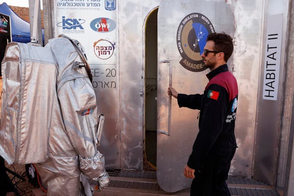 An astronaut from a team from Europe and Israel walks dressed in a spacesuit prepares to enter a sealed habitat during a training mission for planet Mars at a site that simulates an off-site station at the Ramon Crater in Mitzpe Ramon in Israel’s southern Negev desert on October 10, 2021. – Six astronauts from Portugal, Spain, Germany, the Netherlands, Austria, and Israel will be cut off from the world for a month, from October 4-31, only able leave their habitat in spacesuits as if they were on Mars. Their mission, the AMADEE-20 Mars simulation, will be carried out in a Martian terrestrial analog and directed by a dedicated Mission Support Center in Austria, to conduct experiments ahead of future human and robotic Mars exploration missions. (Photo by JACK GUEZ / AFP) (Photo by JACK GUEZ/AFP via Getty Images)