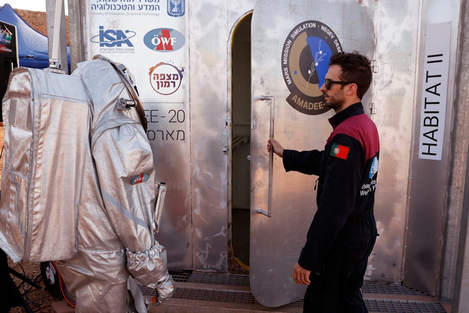 An astronaut from a team from Europe and Israel walks dressed in a spacesuit prepares to enter a sealed habitat during a training mission for planet Mars at a site that simulates an off-site station at the Ramon Crater in Mitzpe Ramon in Israel’s southern Negev desert on October 10, 2021. – Six astronauts from Portugal, Spain, Germany, the Netherlands, Austria, and Israel will be cut off from the world for a month, from October 4-31, only able leave their habitat in spacesuits as if they were on Mars. Their mission, the AMADEE-20 Mars simulation, will be carried out in a Martian terrestrial analog and directed by a dedicated Mission Support Center in Austria, to conduct experiments ahead of future human and robotic Mars exploration missions. (Photo by JACK GUEZ / AFP) (Photo by JACK GUEZ/AFP via Getty Images)