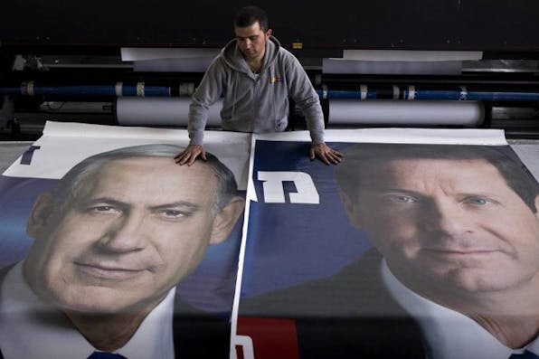 *A worker lays out posters of Benjamin Netanyahu and Isaac Herzog during the 2015 Israeli election campaign.* Grossman Response