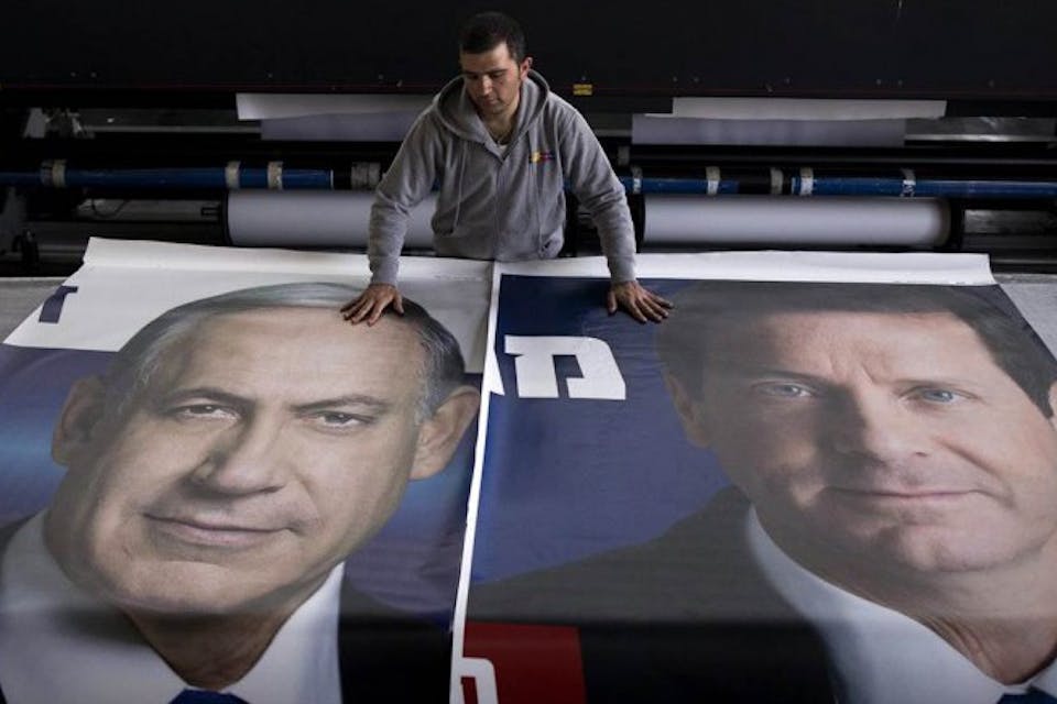 *A worker lays out posters of Benjamin Netanyahu and Isaac Herzog during the 2015 Israeli election campaign.* Grossman Response