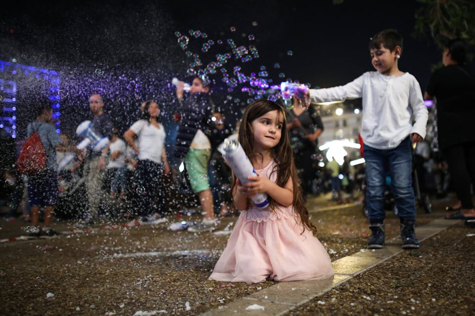 A girl plays with a can of foam spray while a boy uses a toy gun to make soap bubbles during celebrations marking Israel’s 69th Independence Day in Tel Aviv, Israel, May 01, 2017. (Photo by Corinna Kern/NurPhoto via Getty Images)