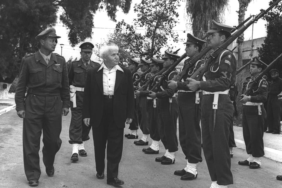 David Ben-Gurion, accompanied by Moshe Dayan, inspecting a guard of honor outside his office in Tel Aviv in 1955. *HANS PIN/Israeli National Photo Collection*. P.M. DAVID BEN GURION ACCOMPANIED BY CHIEF OF STAFF MOSHE DAYAN INSPECTING A GUARD OF HONOR OUTSIDE HIS OFFICE AT HAKIRYA IN TEL AVIV.
øàù äîîìùä ãåã áï âåøéåï îìååä ò”é äøîèë”ì îùä ãééï ñå÷ø îùîø ëáåã, îçåõ ìîùøãå á÷øééä áúì àáéá.