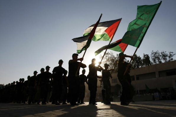 Gazan youths parade with a Hamas flag and Palestinian flag at a Hamas-run summer camp in Rafah in 2009. *Said Khatib/AFP via Getty Images*. TOPSHOT – Palestinian youths parade with a Hamas flag (green-front) and their national flag bearing the writing “There is no God but God and Mohammed is his Prophet” at a Hamas-run summer camp in Rafah, southern Gaza Strip, on August 11, 2009. The Islamist movement Hamas is holding summer camps throughout the Gaza Strip, where participants from 14 to 17 years old take part in physical exercises and mental training. AFP PHOTO/SAID KHATIB (Photo by Said KHATIB / AFP) (Photo by SAID KHATIB/AFP via Getty Images)
