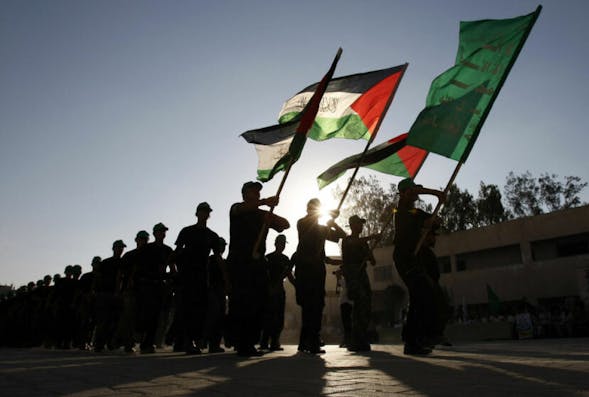 TOPSHOT – Palestinian youths parade with a Hamas flag (green-front) and their national flag bearing the writing “There is no God but God and Mohammed is his Prophet” at a Hamas-run summer camp in Rafah, southern Gaza Strip, on August 11, 2009. The Islamist movement Hamas is holding summer camps throughout the Gaza Strip, where participants from 14 to 17 years old take part in physical exercises and mental training. AFP PHOTO/SAID KHATIB (Photo by Said KHATIB / AFP) (Photo by SAID KHATIB/AFP via Getty Images)