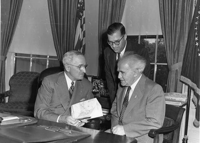 President Harry S. Truman (left) meets with Israeli Prime Minister David Ben-Gurion (right) and Israeli Ambassador Abba Eban (standing) in a gift ceremony in the Oval Office. President Harry S. Truman (left) meets with Israeli Prime Minister David Ben-Gurion (right) and Israeli Ambassador Abba Eban (standing) in a gift ceremony in the Oval Office.