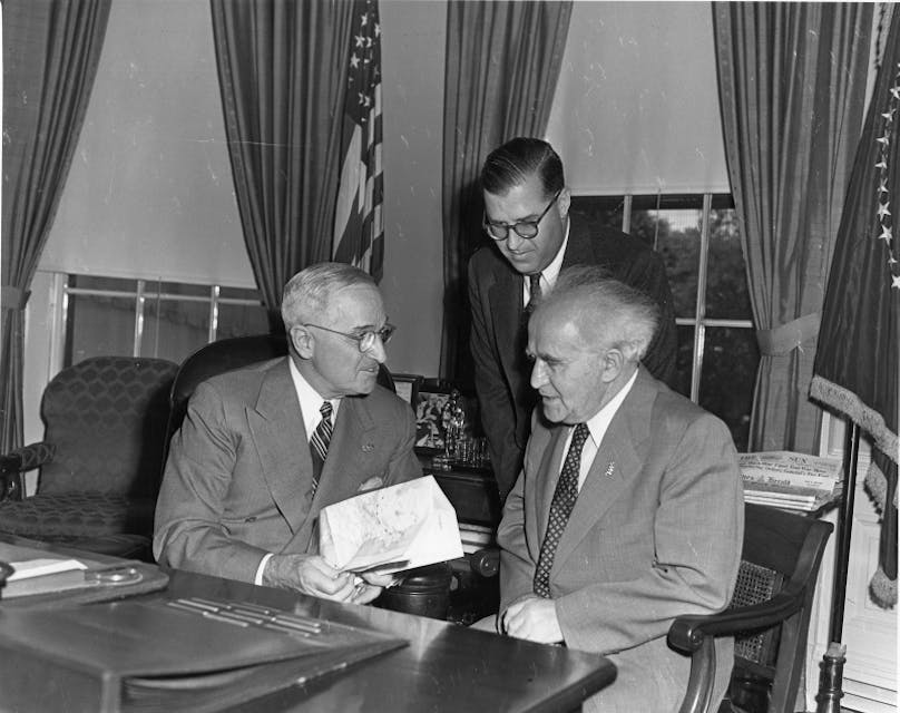 President Harry S. Truman (left) meets with Israeli Prime Minister David Ben-Gurion (right) and Israeli Ambassador Abba Eban (standing) in a gift ceremony in the Oval Office.