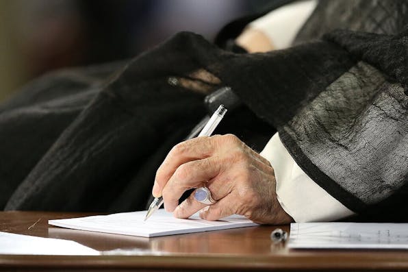 Ali Khamenei signing a document. Wikimedia Commons.