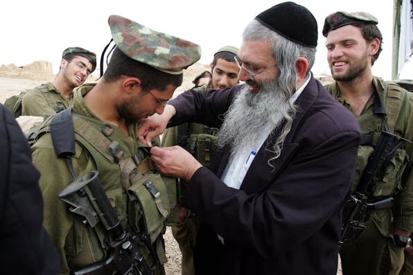 A member of a haredi IDF battalion receives a unit pin from a rabbi, March 2007. (Menahem Kahana/AFP via Getty Images) A member of a haredi IDF battalion receives a unit pin from a rabbi, March 2007. (Menahem Kahana/AFP via Getty Images)