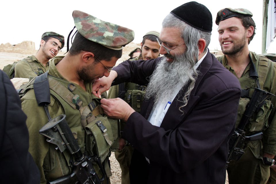 A member of a haredi IDF battalion receives a unit pin from a rabbi, March 2007. (Menahem Kahana/AFP via Getty Images) A member of a haredi IDF battalion receives a unit pin from a rabbi, March 2007. (Menahem Kahana/AFP via Getty Images)