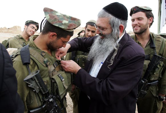 A member of a haredi IDF battalion receives a unit pin from a rabbi, March 2007. (Menahem Kahana/AFP via Getty Images)