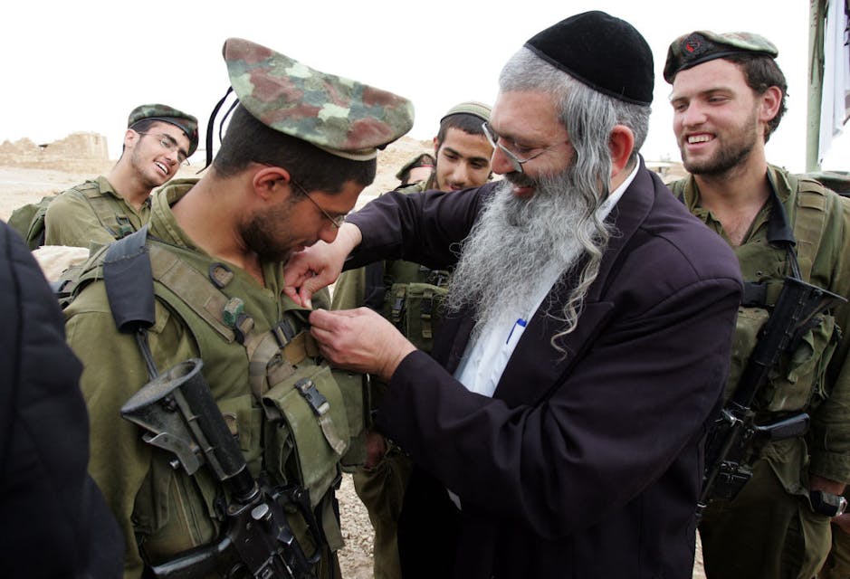 A member of a haredi IDF battalion receives a unit pin from a rabbi, March 2007. (Menahem Kahana/AFP via Getty Images)