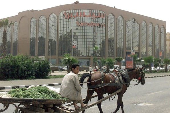 A boy sells greens in front of the British chain store Sainsbury's in Cairo, April 2000. (Marwan Naamani/AFP via Getty Images) A boy sells greens in front of the British chain store Sainsbury's in Cairo, April 2000. (Marwan Naamani/AFP via Getty Images)