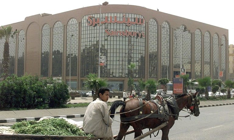 A boy sells greens in front of the British chain store Sainsbury's in Cairo, April 2000. (Marwan Naamani/AFP via Getty Images) A boy sells greens in front of the British chain store Sainsbury's in Cairo, April 2000. (Marwan Naamani/AFP via Getty Images)