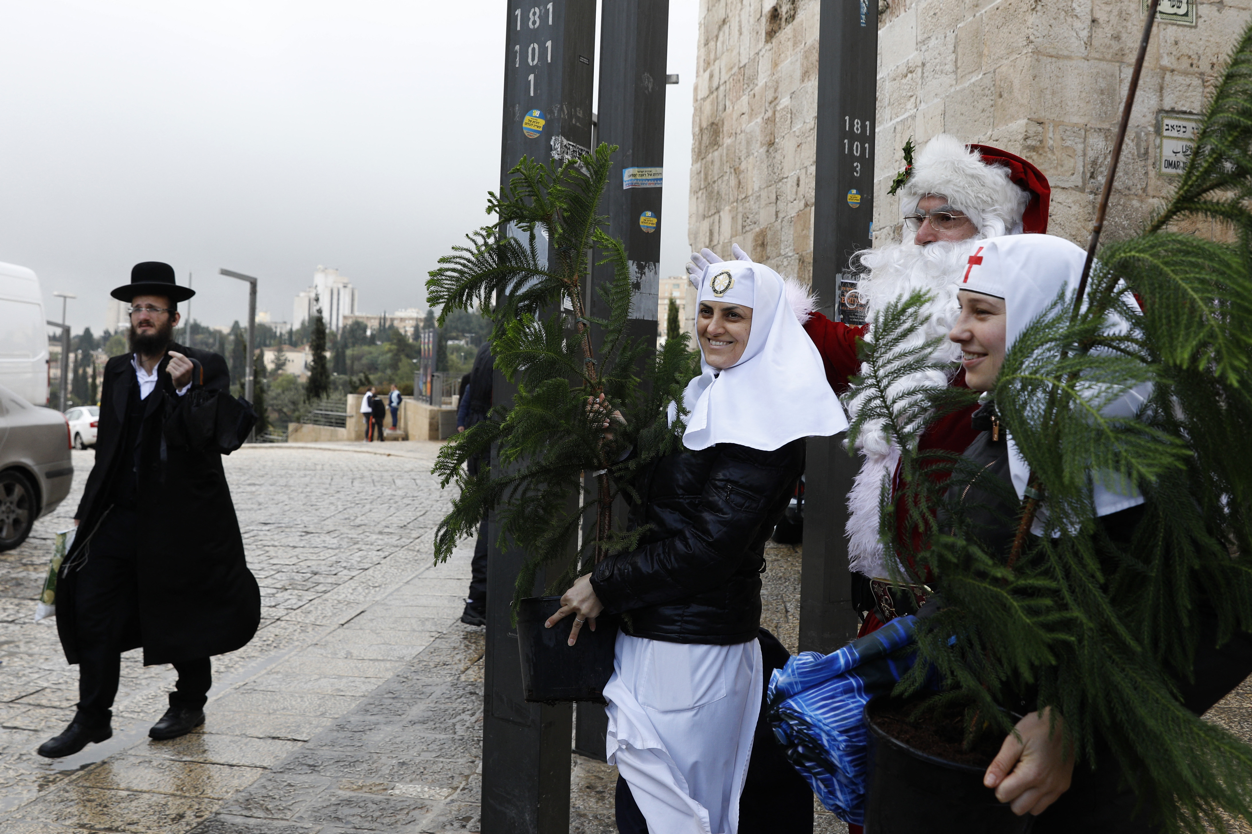 A Jewish man walks past a man dressed as Santa Claus and Russian Orthodox nuns in Jerusalem's Old City. (Photo by Gali TIbbon/ AFP via Getty Images.)